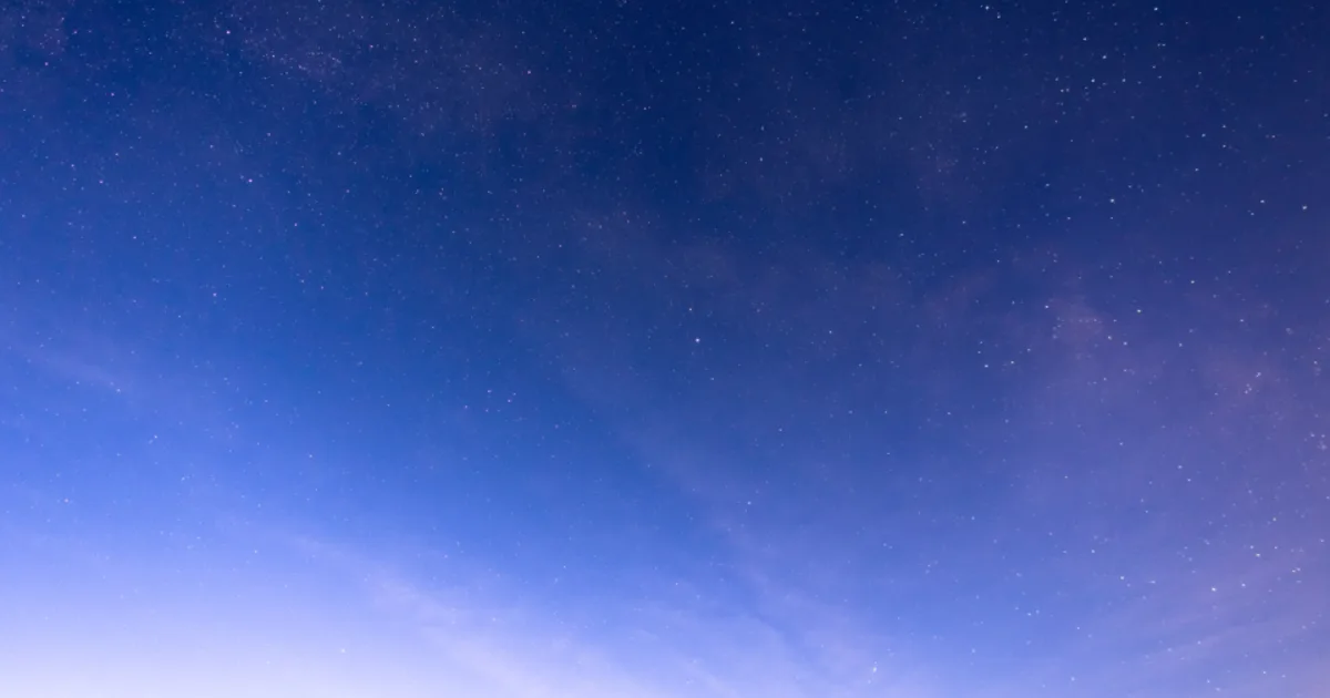 The Milky Way arching across a deep blue starry night sky