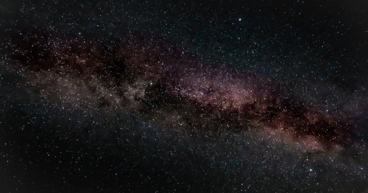 A clear, star-filled dark night sky over a quiet horizon